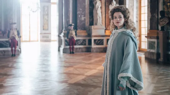 Marie Antoinette played by Emilia Schüle standing alone looking into the distance 
